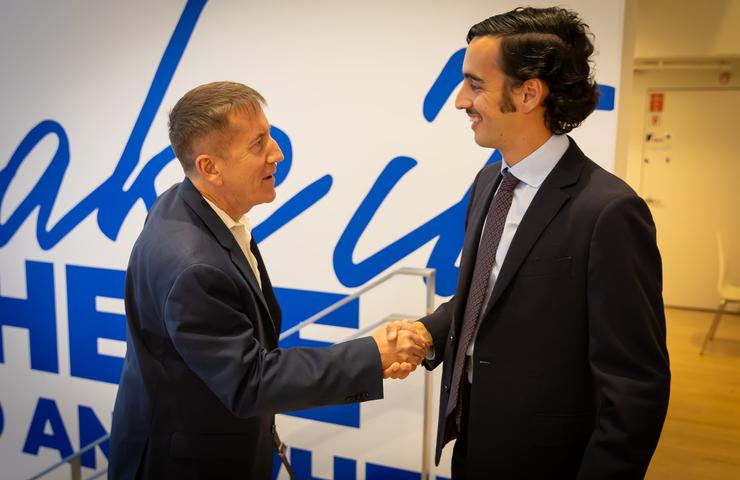 Two men shake hands in a professional setting.