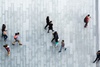 Aerial view of multiple people walking on a patterned pavement.