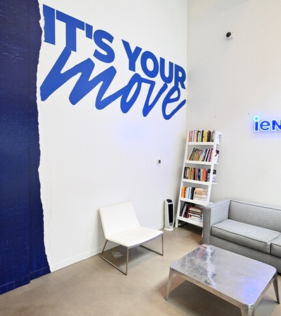 A modern lounge area featuring a blue and white mural with the phrase 'IT'S YOUR MOVE'.