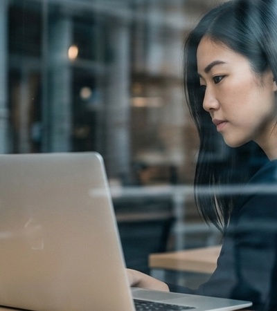 A woman is focused on her laptop while sitting at a café.