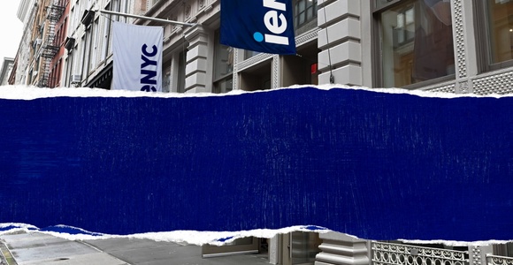 A street view showcasing a building with a blue sign.