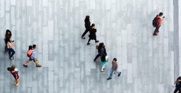 Aerial view of multiple people walking on a patterned pavement.